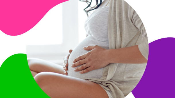 Frau mit fortgeschrittener Schwangerschaft sitz auf dem Bett und hält sich ihren Baby-Bauch